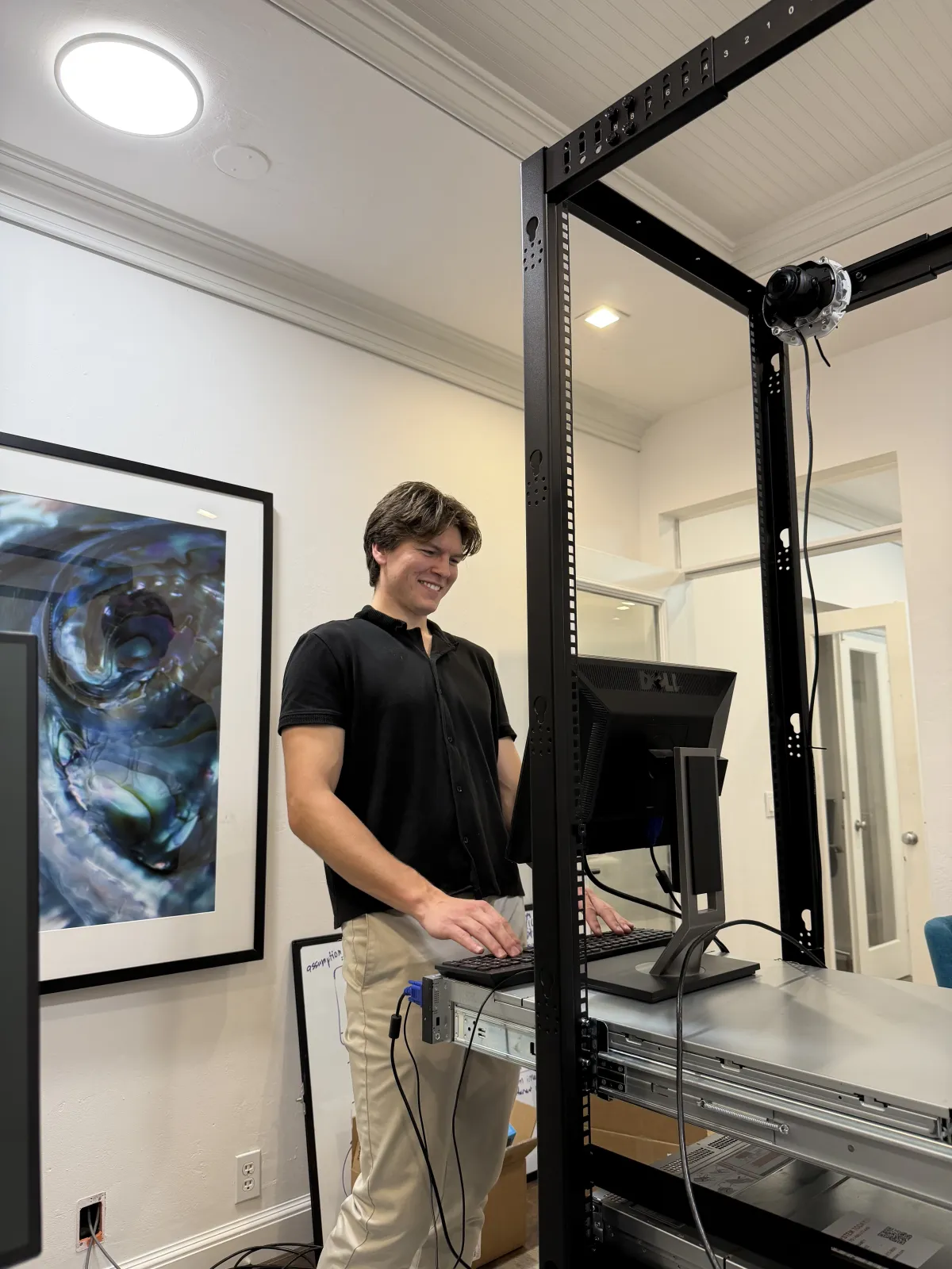 An EdgeTrace founder working at an open server rack, an on-prem appliance with a camera mounted on it